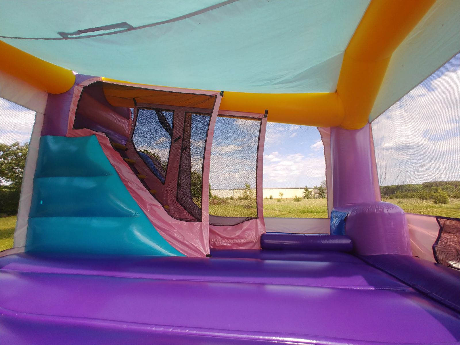 Interior view of slide and climbing wall area inside bounce house rental from Froggy Hops